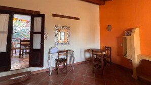 A room with a wooden ceiling, a tiled floor, a table with chairs, a mirror on the wall, and a door leading to an outdoor area. - Habitación Papa Chuy (Segundo piso) (San Francisco)