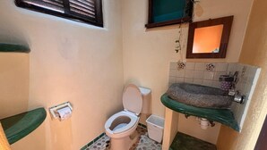 A compact bathroom with a toilet, sink, and a small window. - Habitación Papa Chuy (Segundo piso) (San Francisco)
