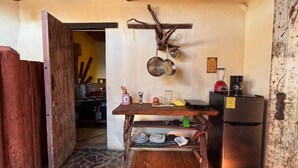 A rustic kitchen with a wooden table, hanging pots, a refrigerator, and a stone floor. - Habitación Luisa (Segundo piso) (San Francisco)