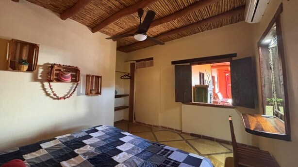 A bedroom with a bed, a ceiling fan, a window, and a door leading to another room. - Habitación Luisa (Segundo piso) (San Francisco)