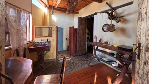 A rustic kitchen with wooden beams, a stone floor, and a wooden table. - Habitación Luisa (Segundo piso) (San Francisco)