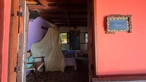 Ein Zimmer mit einem Bett, einem Sessel und einem Moskitonetz.