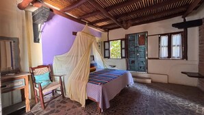 Ein Zimmer mit Bett, Stuhl, Tisch und Fenster.