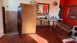 A kitchen with a brick wall, wooden floor, and a red wall. - Habitación Beto-Segundo piso (San Francisco)