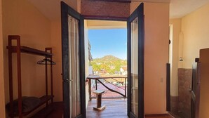 An open doorway leading to a balcony with a view of a hill and buildings. - Habitación Beto-Segundo piso (San Francisco)