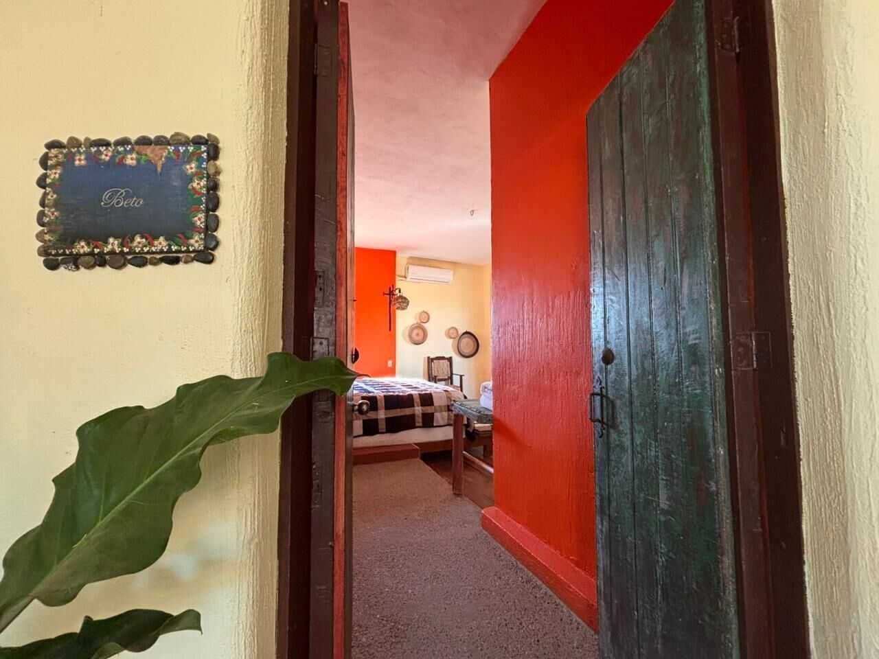 Un pasillo que conduce a un dormitorio con una cama, un cuadro en la pared y una puerta.