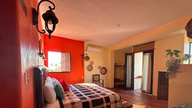 A bedroom with a bed, a wooden bench, a window, and a door leading to a balcony. - Habitación Beto-Segundo piso (San Francisco)