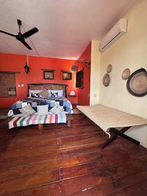 Een kamer met een bed, een plafondventilator, een open haard en een wandairconditioner.