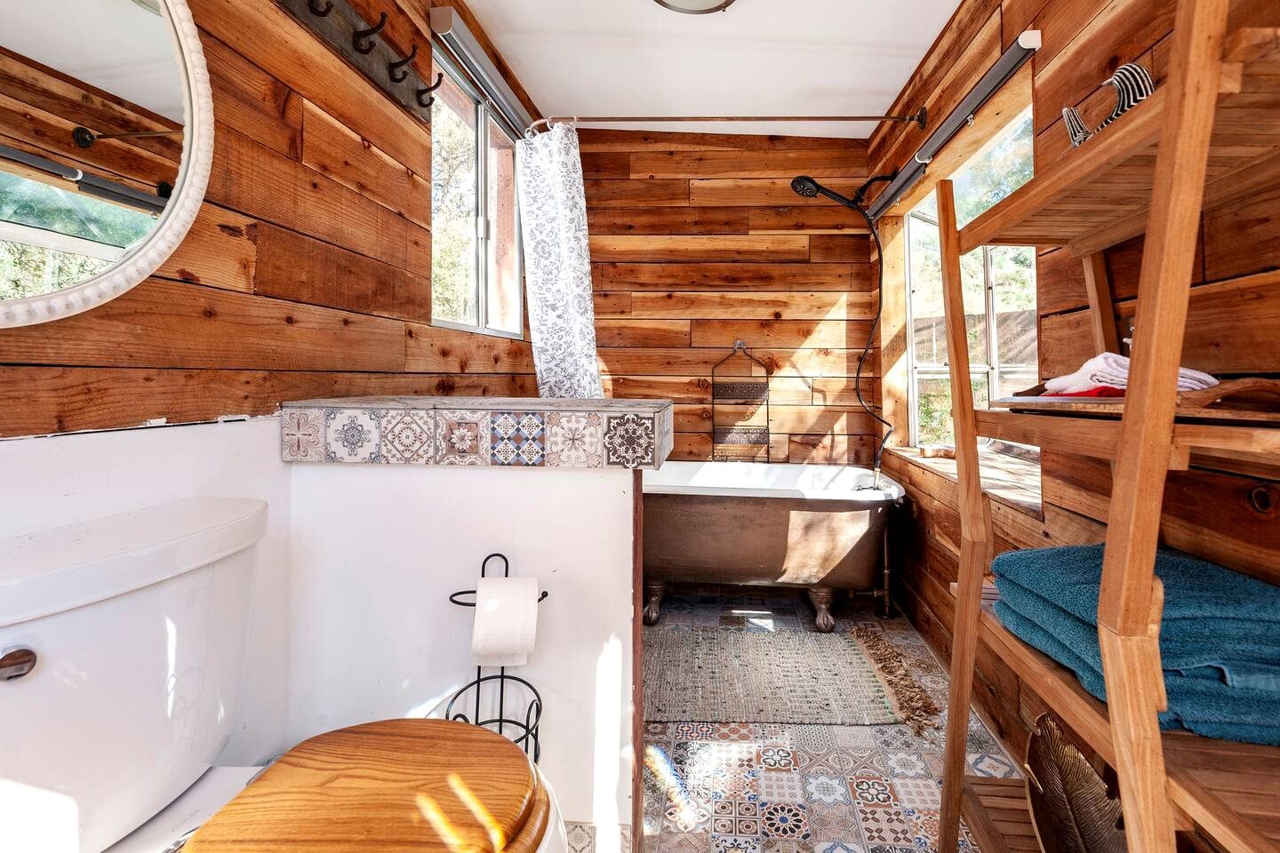 Une salle de bain rustique, aménagée dans une cabane en bois, avec des toilettes, un lavabo et une baignoire.