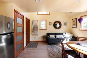 A modern kitchen with a stainless steel refrigerator, wooden cabinets, and a dining area with a table and chairs.