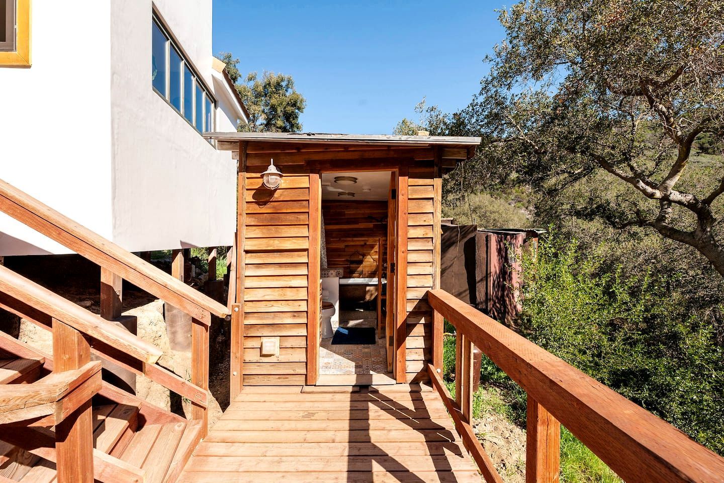 A wooden staircase leading to a building with a white exterior and a wooden deck.