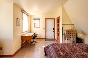 A bedroom with a bed, a desk, and a chair.