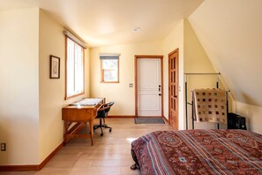 A bedroom with a bed, a desk, and a chair.