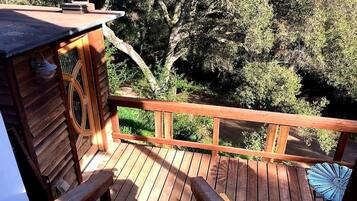 A wooden deck with a railing, a small wooden structure, and a view of trees.