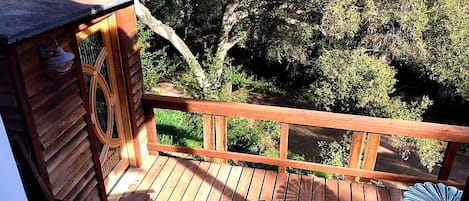 A wooden deck with a railing, a small wooden structure, and a view of trees.