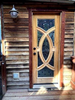 A wooden door with a decorative glass panel and a metal light fixture above it.