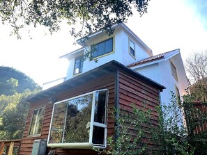 A two-story house with a large window on the ground floor and a smaller window on the upper floor.