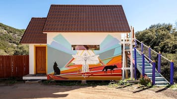 Un bâtiment orné d’une fresque murale, doté d’une porte en bois et d’un escalier.