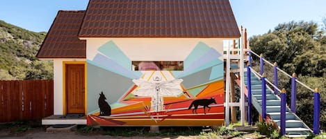 Un edificio con un mural, una puerta de madera y una escalera.