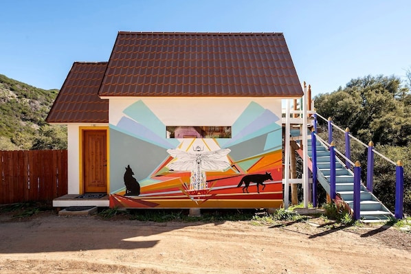 A building with a mural, a wooden door, and a staircase.