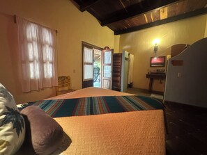 Quarto com cama, cadeira, porta, pia e geladeira.