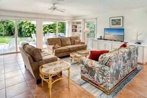 A living room with a sofa, two chairs, a coffee table, a TV, and a bookshelf.