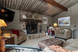 Ein gemütliches Wohnzimmer mit Kamin, Fernseher und bequemen Sitzgelegenheiten.