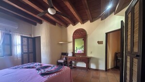 Una camera da letto con un letto, una cassettiera, uno specchio e una ventola a soffitto.