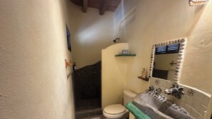 Un bagno con lavandino in pietra, un water e uno spazio doccia.
