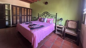 Una camera da letto con un letto, una sedia, un comodino, una ventola a soffitto e un armadio.