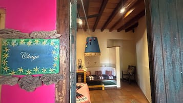 A narrow hallway with a wooden ceiling, a bed with patterned bedding, and a sign reading 'Chayo' on the wall.