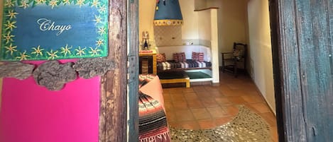 A narrow hallway with a wooden ceiling, a bed with patterned bedding, and a sign reading 'Chayo' on the wall.