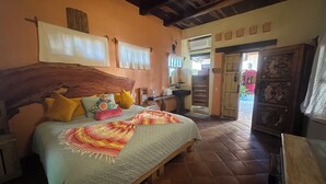 A bedroom with a wooden headboard, a bed with multiple pillows, a bedside table, a wooden wardrobe, and a bathroom with a sink and mirror. - Habitación Triny (Primer piso) (San Francisco)