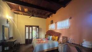 A bedroom with a bed, a nightstand, a mirror, a wooden ceiling, and a door with curtains. - Habitación Triny (Primer piso) (San Francisco)