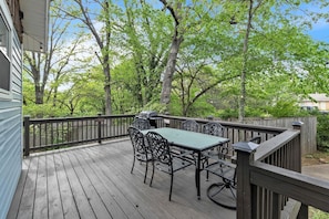 Une terrasse en bois avec une table et des chaises, entourée d’arbres et d’une clôture en bois.