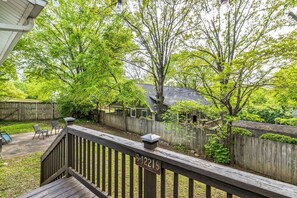 A backyard with a wooden deck, a covered patio area, and a fenced yard.