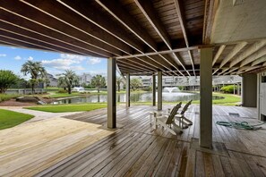 An outdoor wooden deck with a view of a water feature and buildings in the background.