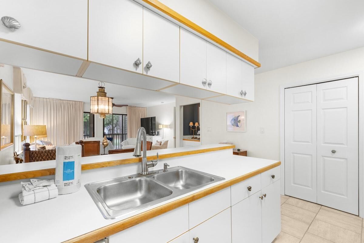 A modern kitchen with a double sink, white cabinetry, and a large mirror above the countertop.