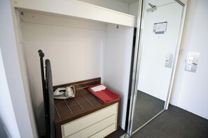 Ein kleiner, gemütlicher Raum mit Bett, Nachttisch und Kleiderschrank.