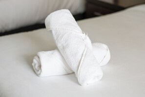 A neatly folded white towel on a bed with a white pillow. - Beachside Studio with Stunning Ocean View (Surfers Paradise)