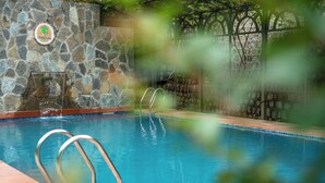 A swimming pool with stone walls and a metal ladder.