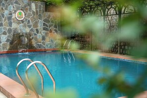 A swimming pool with stone walls and a metal ladder.