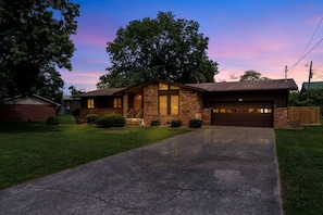 A two-story house with a garage, brick exterior, and a driveway leading to the entrance. - Cozy Cottage with Fire Pit and Barbecue in Pigeon Forge, Tennessee (Pigeon Forge)