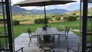 Un patio techado al aire libre con mesa y sillas, con vistas a un paisaje pintoresco.