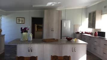 Une cuisine dotée d’un îlot central, de meubles en bois, d’un réfrigérateur et d’un four à micro-ondes.
