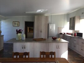 A kitchen with a central island, wooden cabinets, a refrigerator, and a microwave.