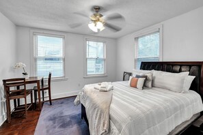 A bedroom with a bed, a desk, and a chair.