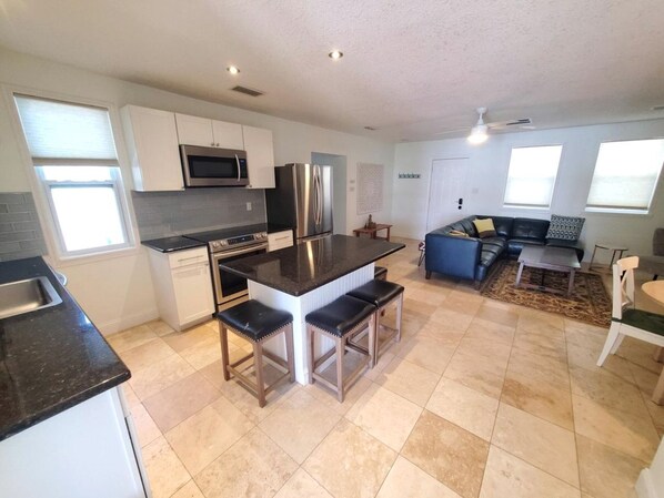 A modern kitchen with a central island, built-in appliances, and a seating area with a sofa and chairs.