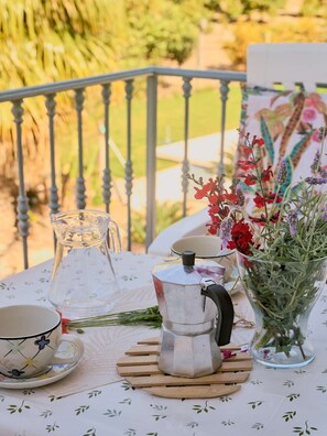 A table with a coffee pot, a cup, a pitcher, and a vase with flowers. - Conjunto Rural Las Rosas 1 by Casasol (Frigiliana)