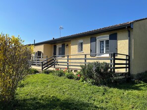 Ein zweistöckiges Gebäude mit Balkon, Treppe und einem kleinen Garten.